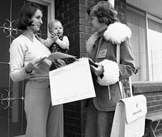 Photograph of a woman census collector on a doorstep talking to a woman holding a child