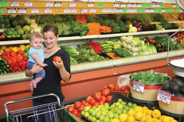 Mother and child in fruit and vegetable aisle of a supermarket