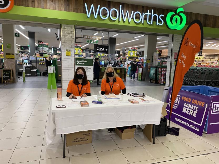 Photo of Census staff at a pop-up hub sitting behind a table outside of Woolworths.