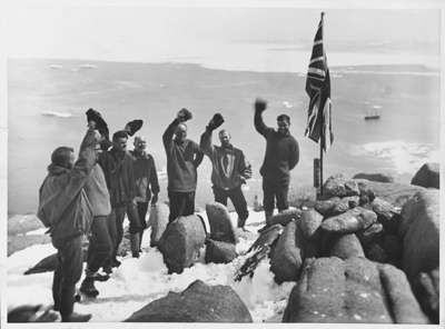 Cheering the flag... A scene on the heights overlooking Proclamation Harbour, Enderby Land, where the Union Jack was raised by Sir Douglas Mawson and his colleagues. At the foot of the flagstaff, official records were buried in a sealed receptacle.