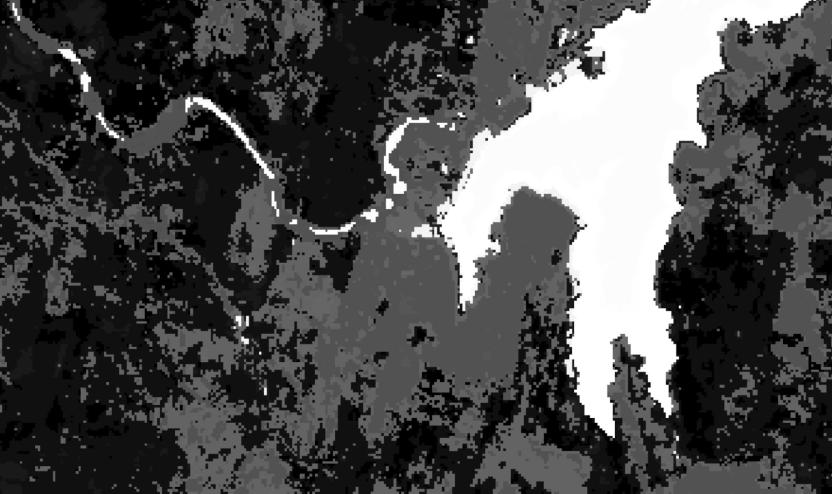 A higher resolution less grainy pixelated image of the same white lake and surrounding grey and black land. The increased definition shows more detail, and a river can now be sen feeding into the lake. Update this alt text to meet standards