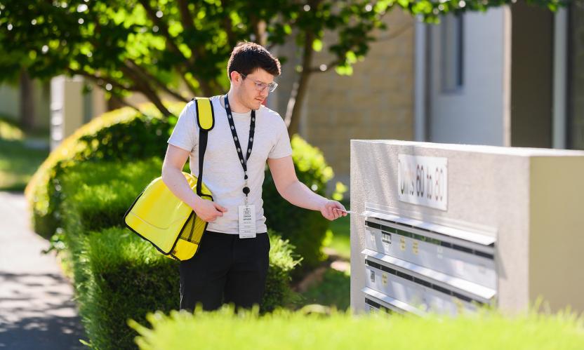 Census staff delivering Census materials into a mailbox.