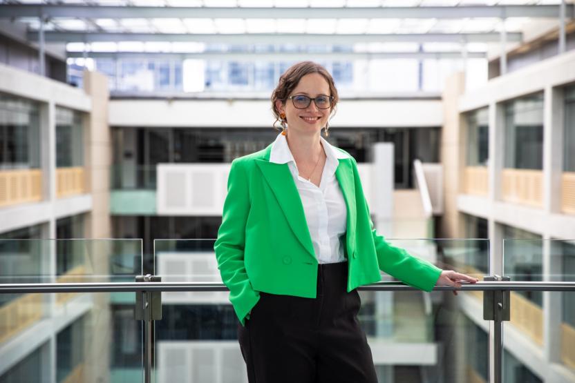 a portrait of Rachael McCririck, looking at the camera and smiling. she is leaning on a railing at ABS house